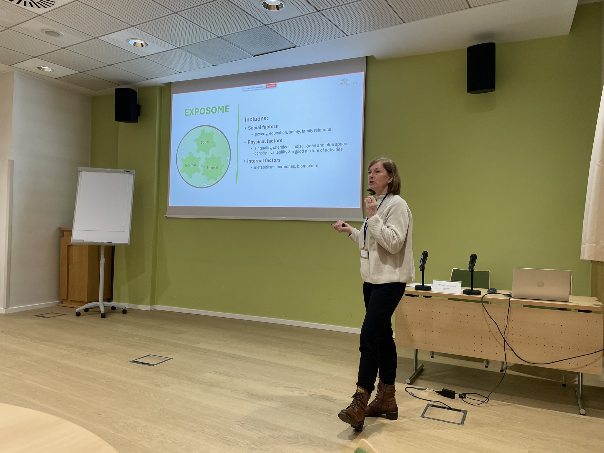 A lady is standing before a screen presenting in a conference hall