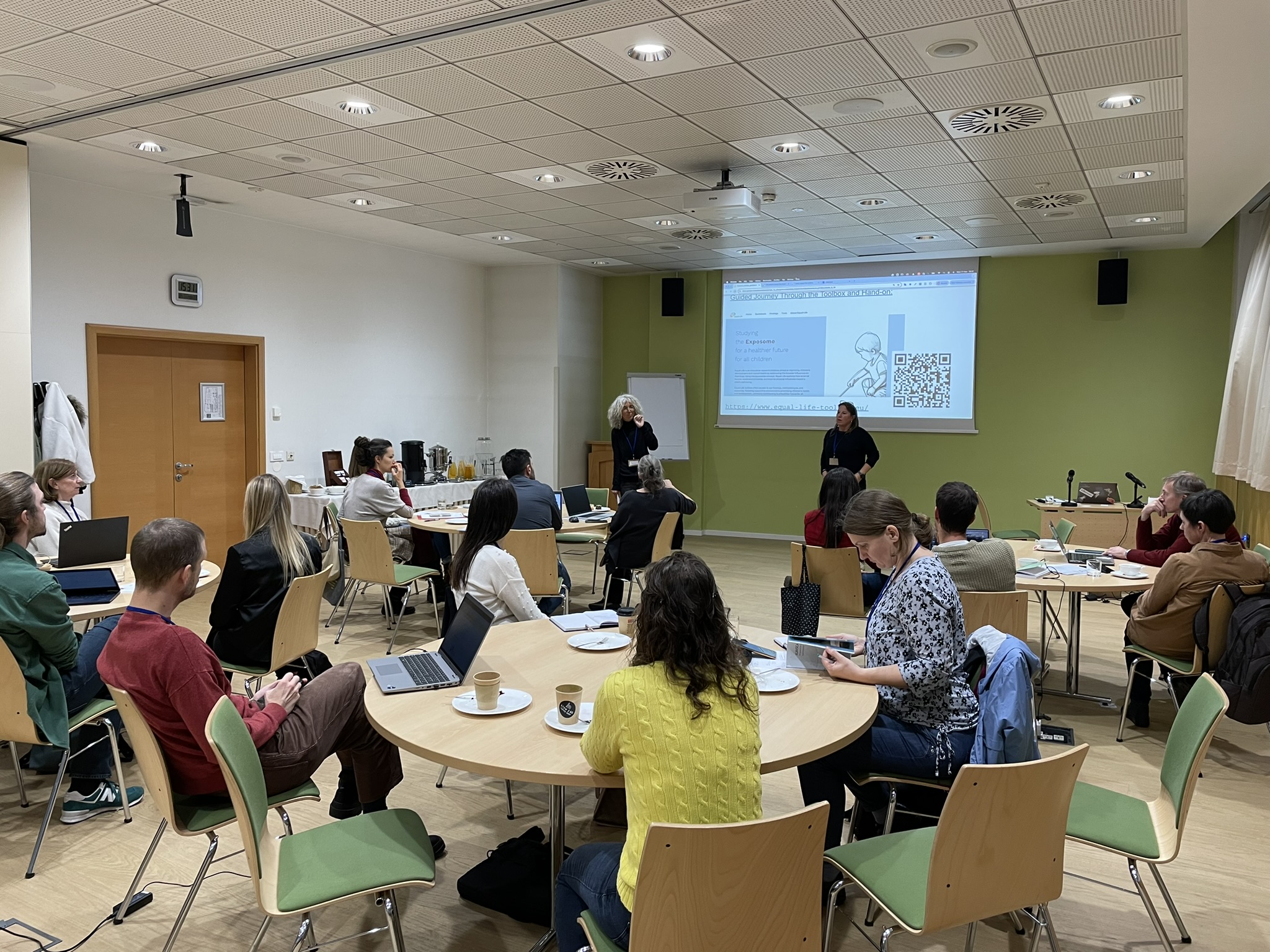 Tables with participants of the Equal-Life training while two people are presenting in front of a screen.