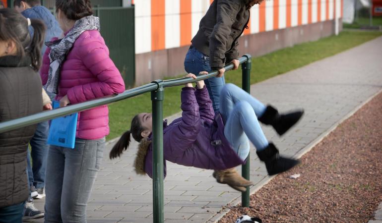 2 Kinderen spelen buiten en doen een koprol om een paal