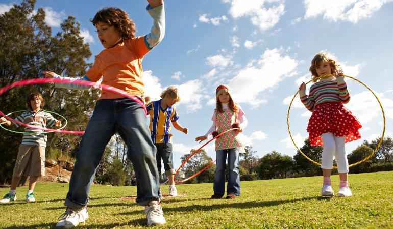 five kids playing outside with hula hoops