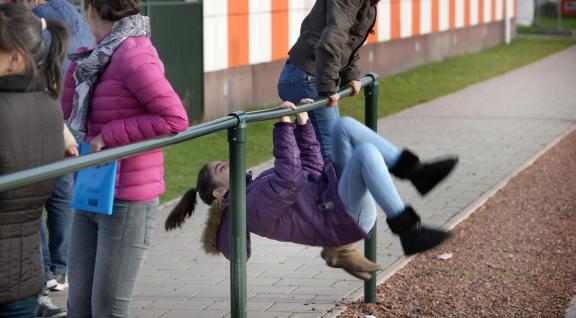 2 Kinderen spelen buiten en doen een koprol om een paal