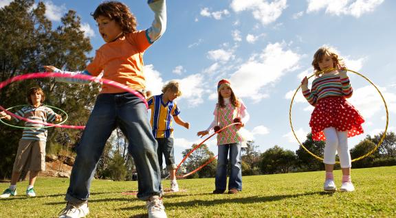 five kids playing outside with hula hoops