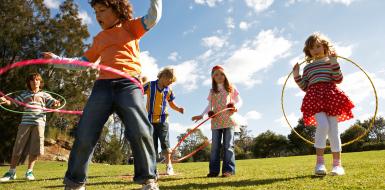 five kids playing outside with hula hoops